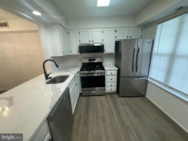 a kitchen with granite countertop a refrigerator stove and sink