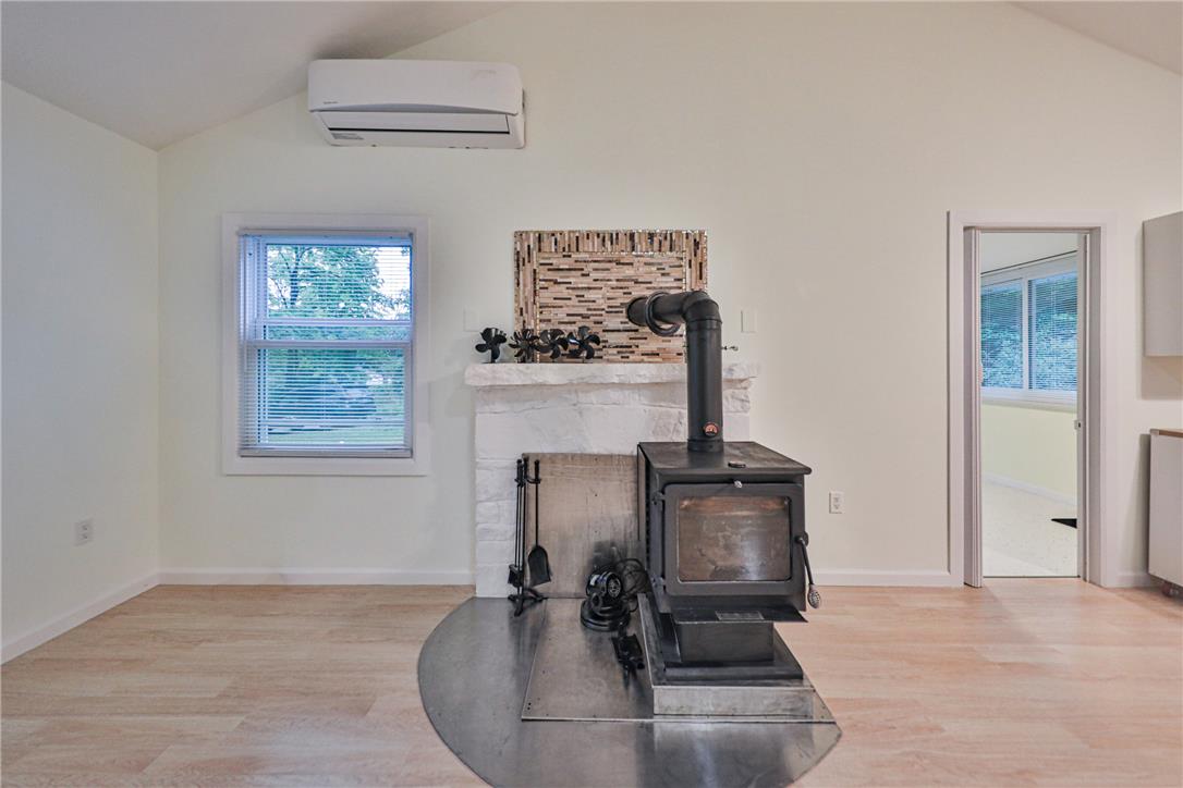 5599 Minks Pond Road Bushkill, PA 18324 - Photo 10 of 64 A comforting wood-burning stove provides warmth, nestled beside a window overlooking greenery.