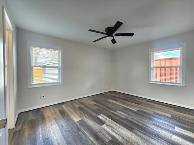 a view of empty room with wooden floor and fan