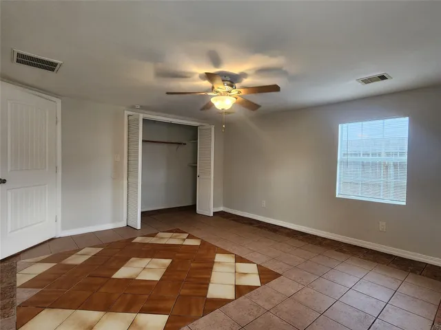 a view of an empty room with chandelier fan