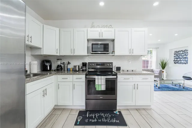 a kitchen with cabinets stainless steel appliances and wooden floor