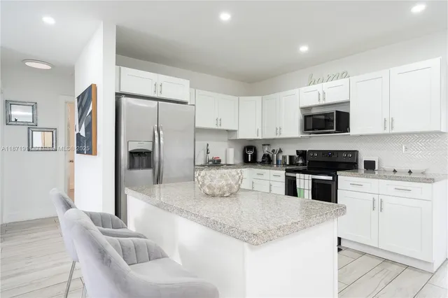 a kitchen with granite countertop white cabinets and stainless steel appliances