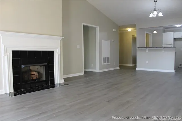 a view of an empty room with wooden floor and a fireplace
