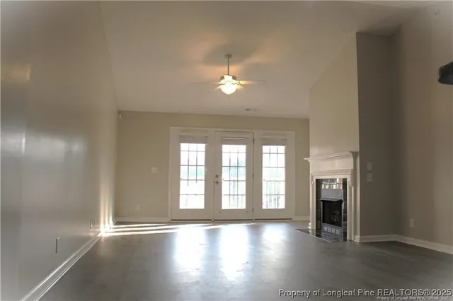 an empty room with wooden floor fireplace and windows