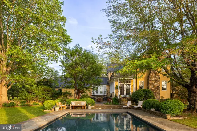 a front view of a house with swimming pool and trees
