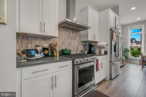 a kitchen with stainless steel appliances granite countertop a stove a refrigerator and a white cabinets