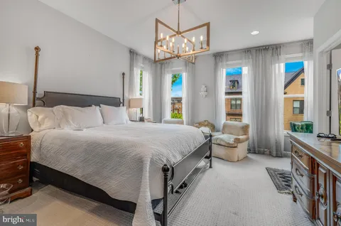 a spacious bedroom with a bed a chandelier and large window