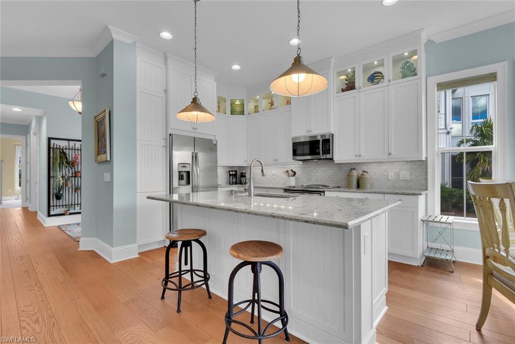 6561 Dominica Drive, Unit 8101 Naples, FL 34113 - Photo 7 of 46 a kitchen with stainless steel appliances granite countertop a sink a stove a refrigerator a dining table and chairs with wooden floor
