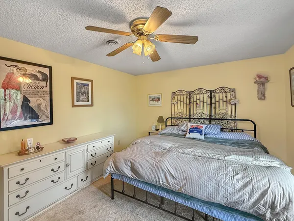 a bedroom with a bed a dresser and a chandelier