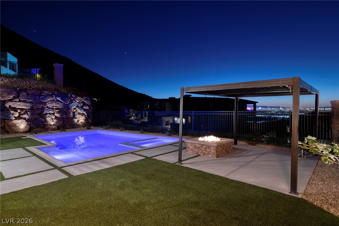 526 Riley Ridge Henderson, NV 89012 - Photo 5 of 10 An illuminated pool and inviting fire pit offer an idyllic setting for evening relaxation.