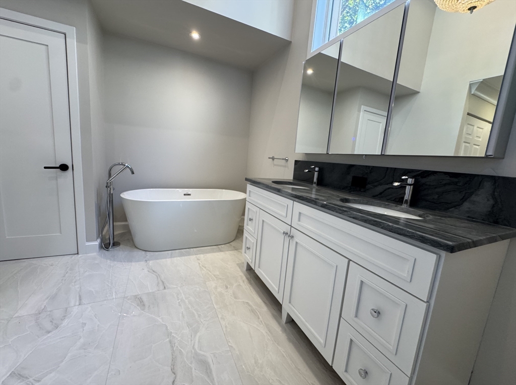 7 Wainwright Road, Unit 13 Winchester, MA 01890 - Photo 17 of 24 a bathroom with a double vanity sink a mirror and a bathtub