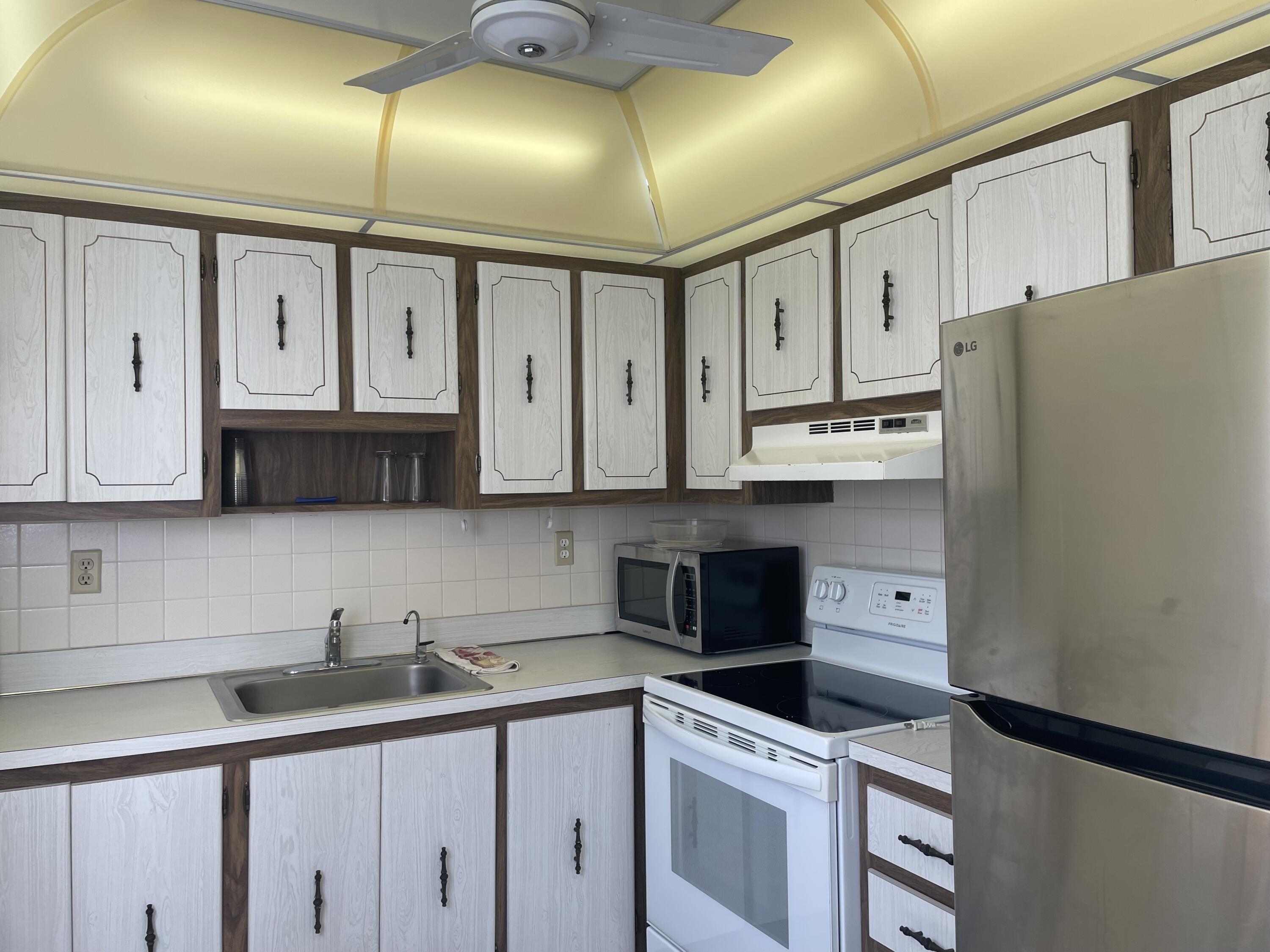 705 Normandy Lane, Unit 705 Delray Beach, FL 33484 - Photo 11 of 37 a kitchen with stainless steel appliances granite countertop a sink a stove and a refrigerator