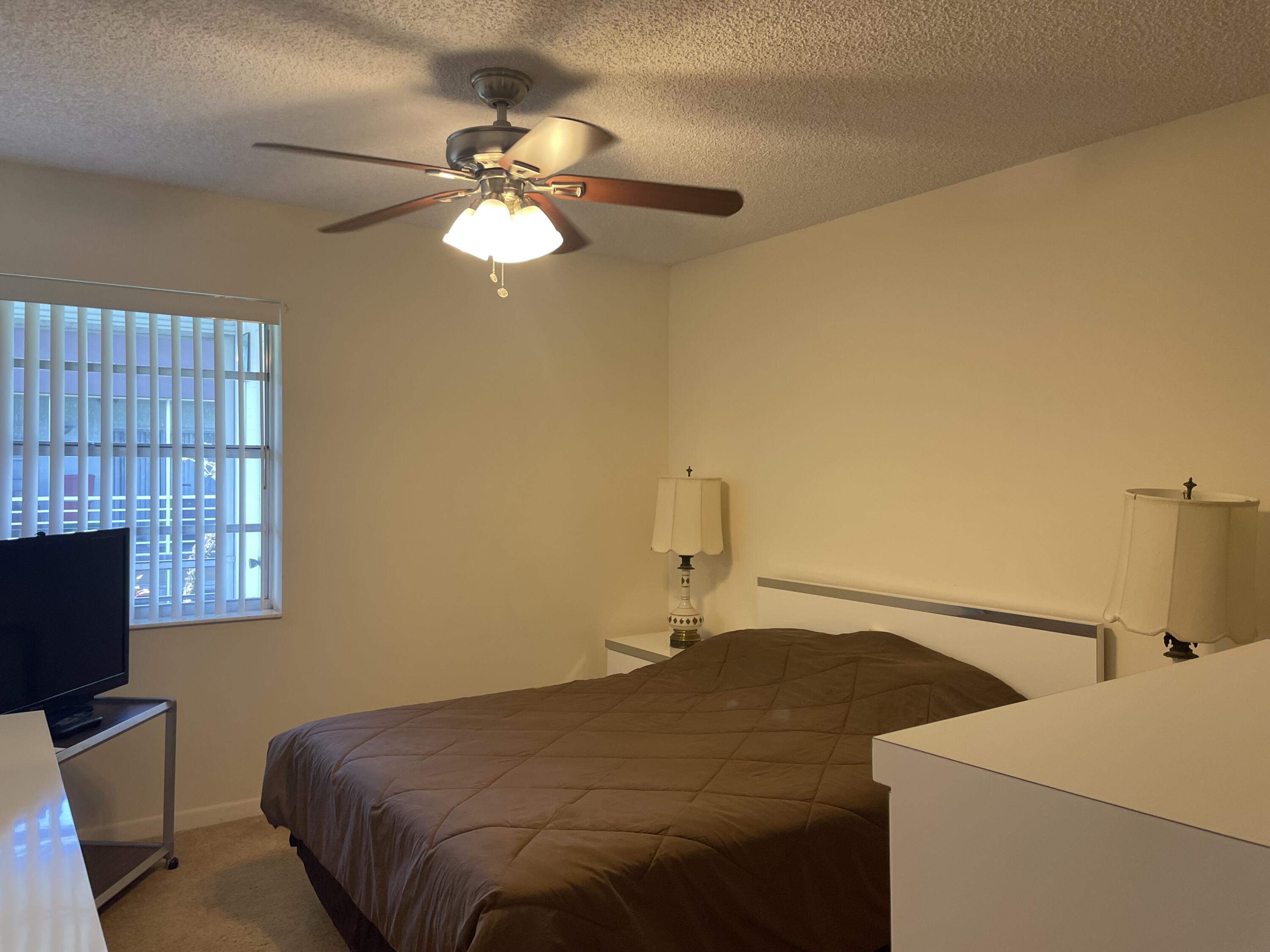 705 Normandy Lane, Unit 705 Delray Beach, FL 33484 - Photo 30 of 37 a bedroom with a bed and a chandelier