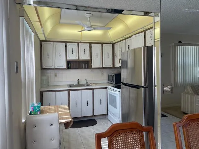 a kitchen with granite countertop a refrigerator a sink and white cabinets
