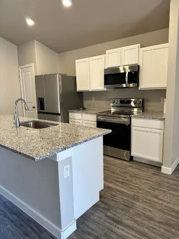 a kitchen with stainless steel appliances granite countertop a sink stove microwave and refrigerator