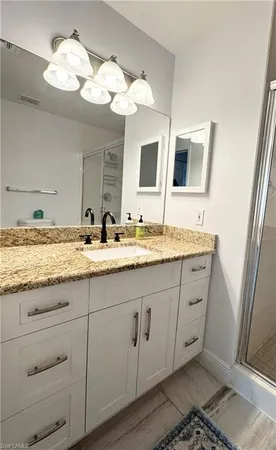 a bathroom with a granite countertop sink and a mirror