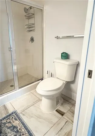 a white toilet sitting next to a bathroom sink and a shower
