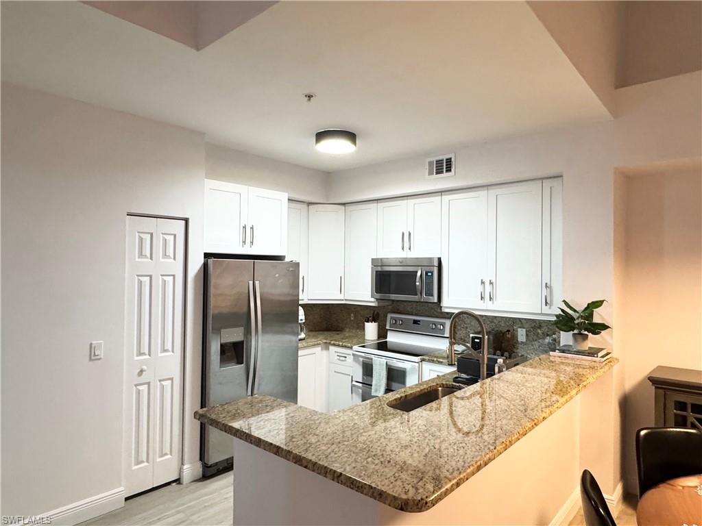 1190 Reserve Way, Unit 304 Naples, FL 34105 - Photo 5 of 20 a kitchen with granite countertop a refrigerator a stove a sink a counter space and cabinets