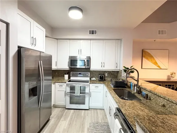 a kitchen with stainless steel appliances granite countertop a sink stove refrigerator and microwave