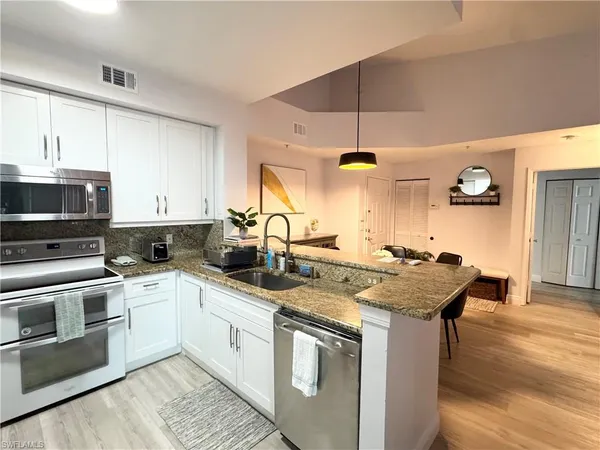 a kitchen with stainless steel appliances granite countertop a sink stove and cabinets