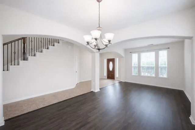 a view of an empty room with wooden floor and a large window