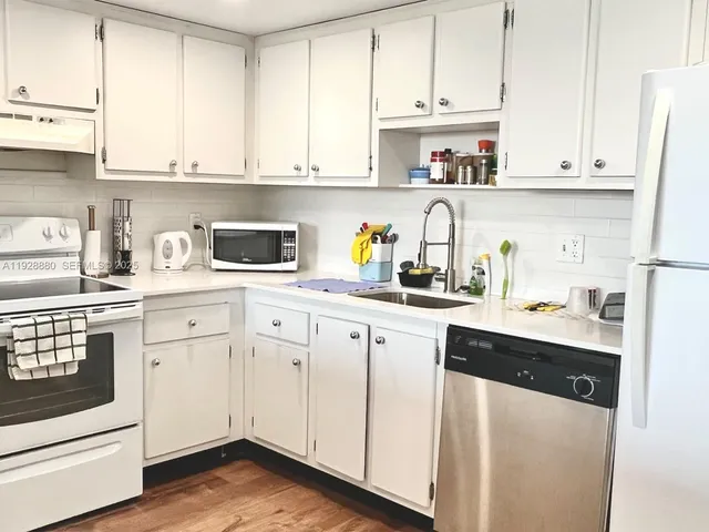 a kitchen with white cabinets and white appliances