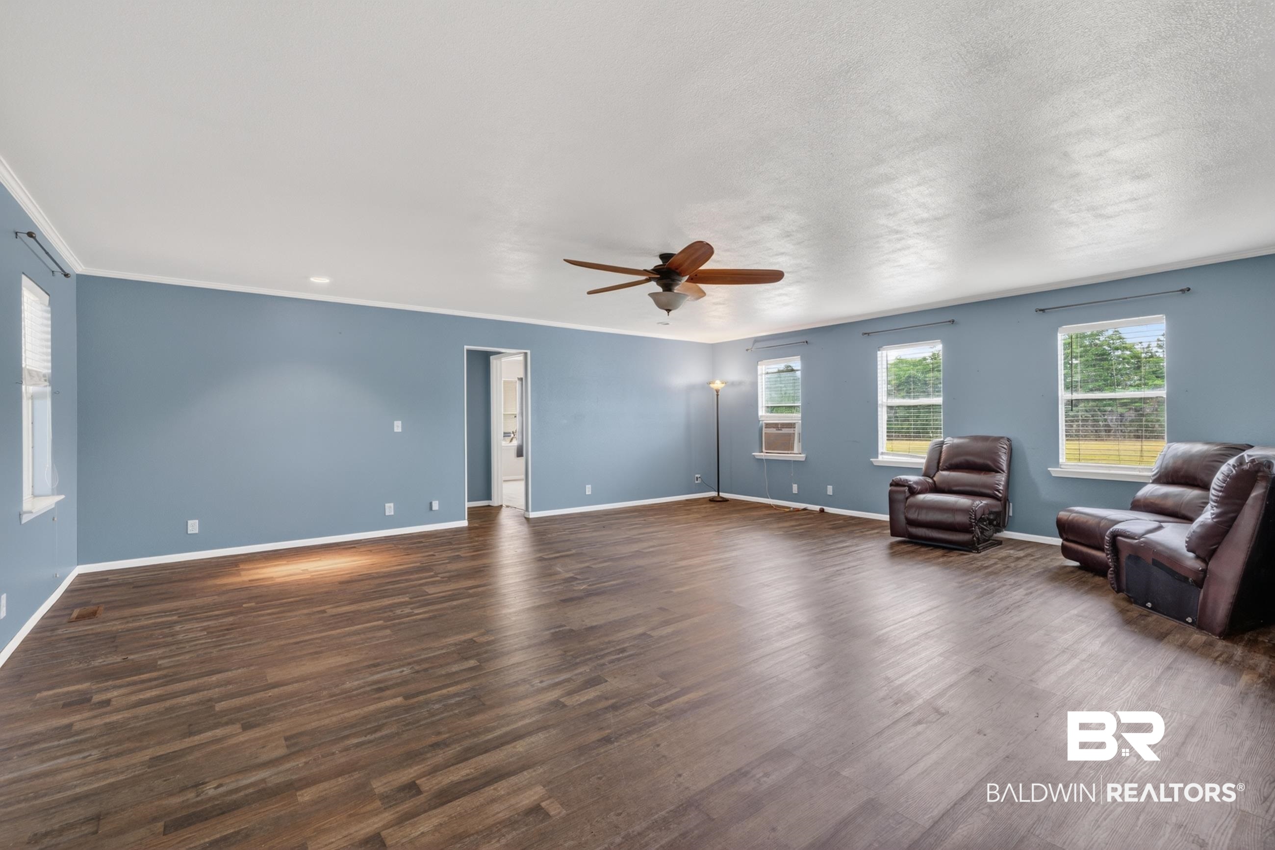 24903 Patterson Road Robertsdale, AL 36567 - Photo 31 of 57 Spacious room featuring wood-finish flooring, light blue walls, and white crown molding
