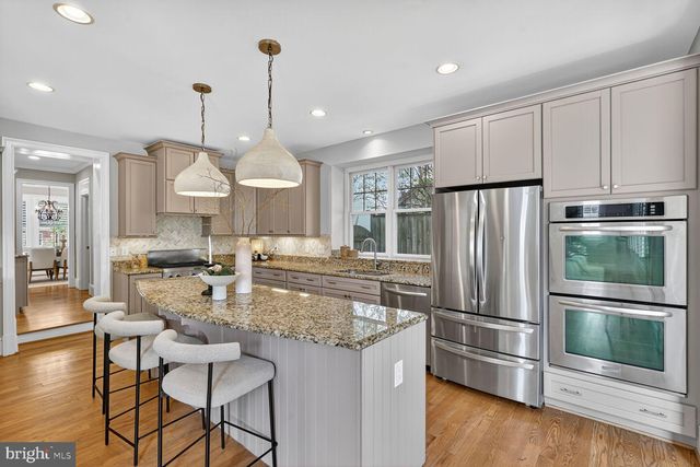 a kitchen with stainless steel appliances granite countertop a refrigerator a sink dishwasher a stove and white cabinets with wooden floor