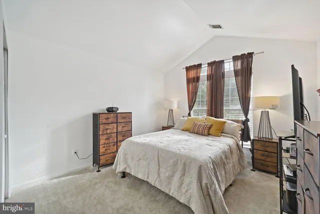 a bedroom with a bed and flat tv screen on the dresser