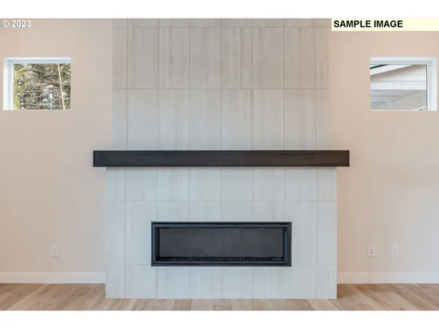 a view of empty room with wooden floor and kitchen