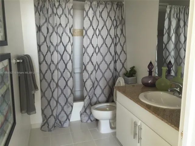 a bathroom with a granite countertop toilet and a sink