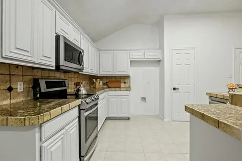 a kitchen with stainless steel appliances granite countertop a stove a sink and a microwave