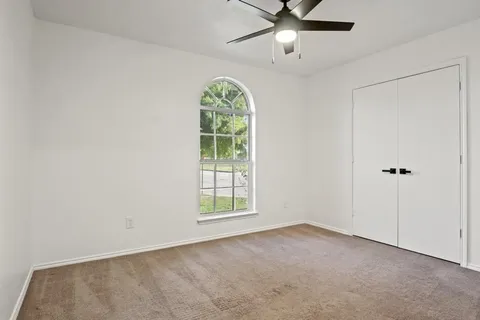 an empty room with windows and fan