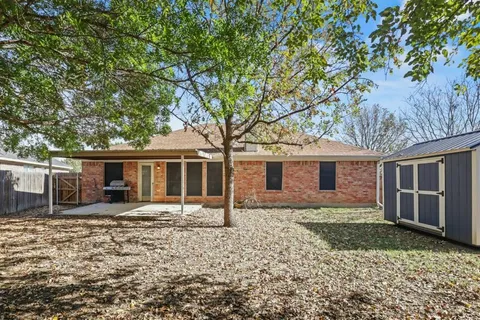 a backyard of a house with yard fire pit and large tree