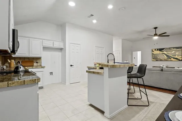 a kitchen with stainless steel appliances granite countertop a stove top oven a sink a dining table and chairs with wooden floor