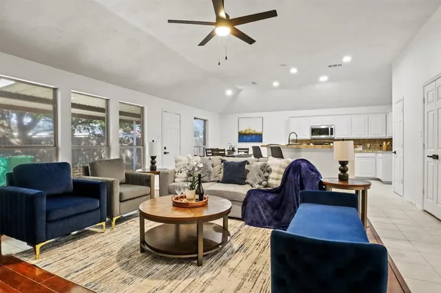 a living room with furniture kitchen view and a large window