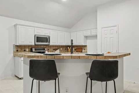 a kitchen with kitchen island granite countertop white cabinets and refrigerator