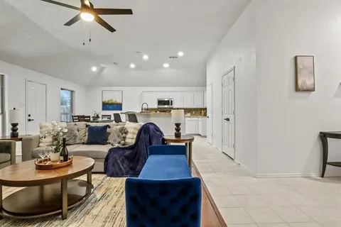 a living room with furniture kitchen view and a wooden floor