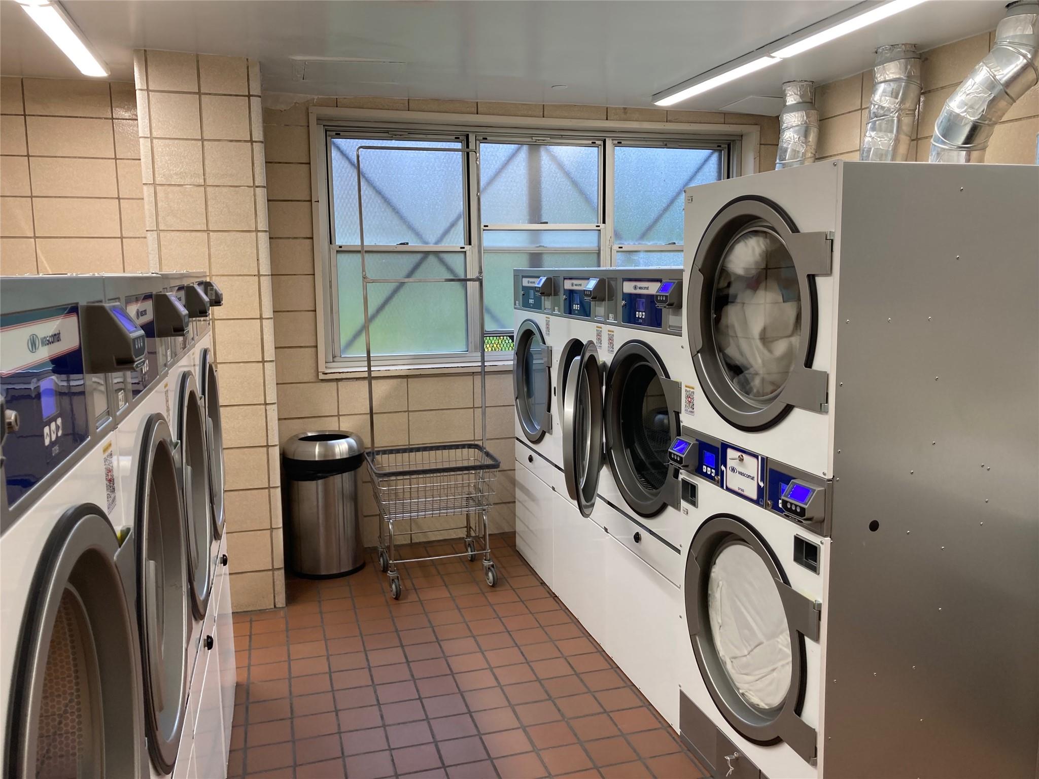 17-85 215th Street, Unit 4B Queens, NY 11360 - Photo 27 of 31 Community laundry room featuring stacked washing machine and dryer, separate washer and dryer, tile patterned flooring, tile walls, and plenty of natural light