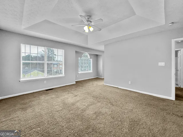 an empty room with windows and chandelier fan