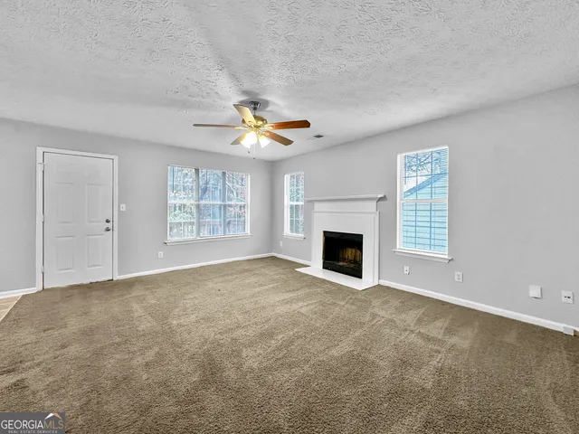 an empty room with windows and fireplace
