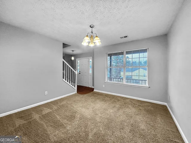 a view of an empty room with chandelier and a window