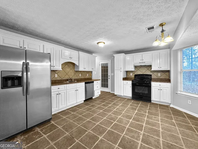 a kitchen with granite countertop a refrigerator and a stove top oven