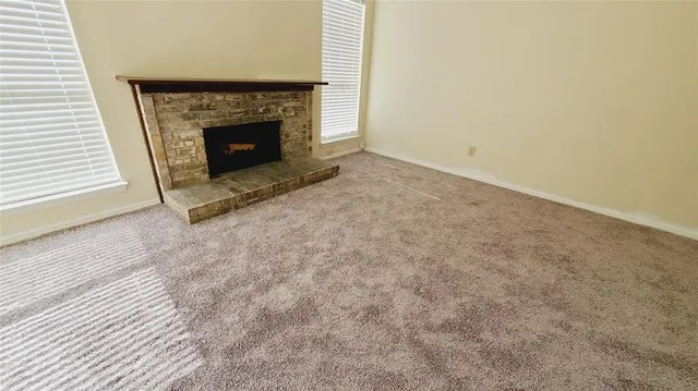 an empty room with wooden floor chandelier and windows