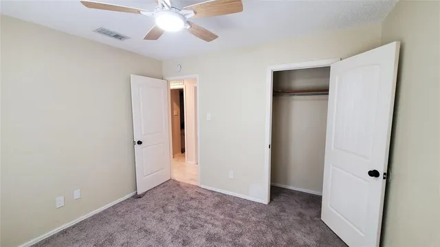 an empty room that has a chandelier fan and a window