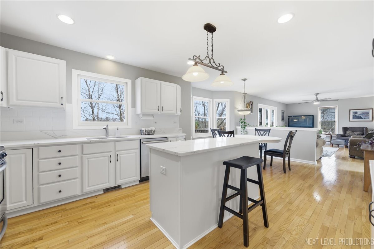 2984 Marshfield Court Elgin, IL 60124 - Photo 11 of 40 a kitchen with stainless steel appliances kitchen island granite countertop a stove a sink a dining table and chairs with wooden floor