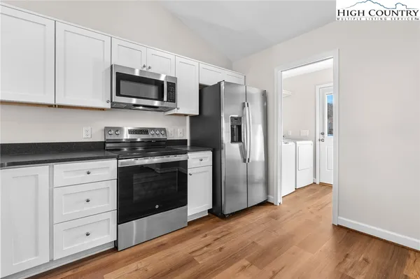 a kitchen with stainless steel appliances granite countertop a refrigerator stove and white cabinets