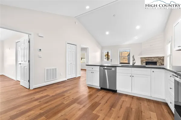 a kitchen with white cabinets and wooden floor