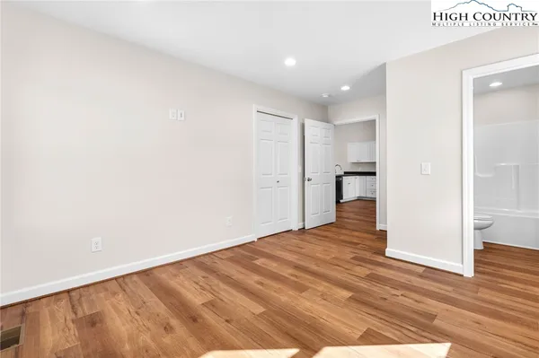 a view of an empty room with wooden floor and a bathroom