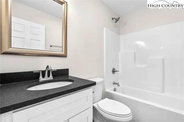 a bathroom with a granite countertop sink toilet a mirror and bathtub